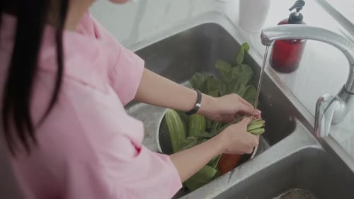 Adult Washing Fresh Vegetables in Kitchen Sink
