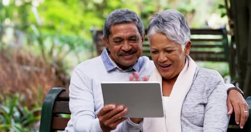 4k video footage of a mature couple making a video call on a digital tablet at the park