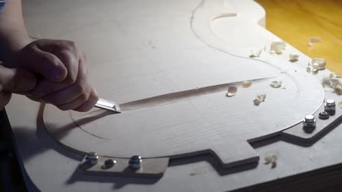 Craftsman Shaping Wood with Carving Tool in Workshop