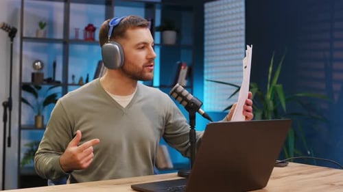 By the laptop. Man with microphone in the studio, conception of podcast.