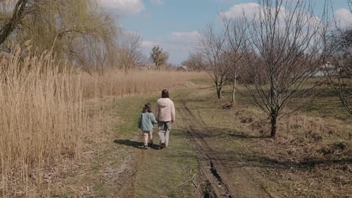 Two Young Girls Walk Along a Grassy Path in the Countryside on a Bright Spring Day Enjoying Peaceful