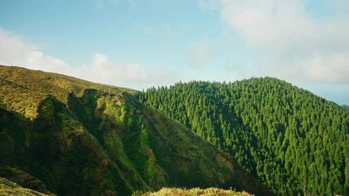 Green picturesque mountain landscape. Scenic rural landmark. Green grass meadow. Blue sky with fluff