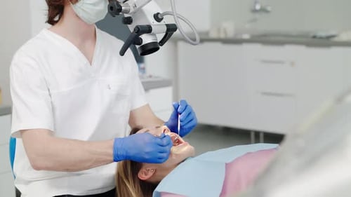 Dentist Examining Female Patient with Microscope in Clinic
