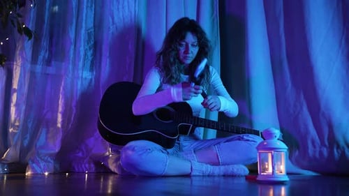 Woman Prepares to Play Guitar for Live Stream