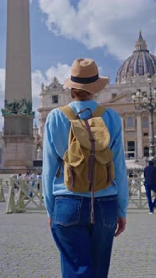 A Girl Tourist in a Hat and with a Backpack Walks Along As She Admires the Iconic St Peters Square