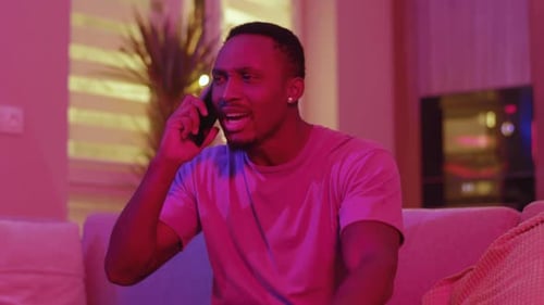 Frustrated man talking on phone in living room