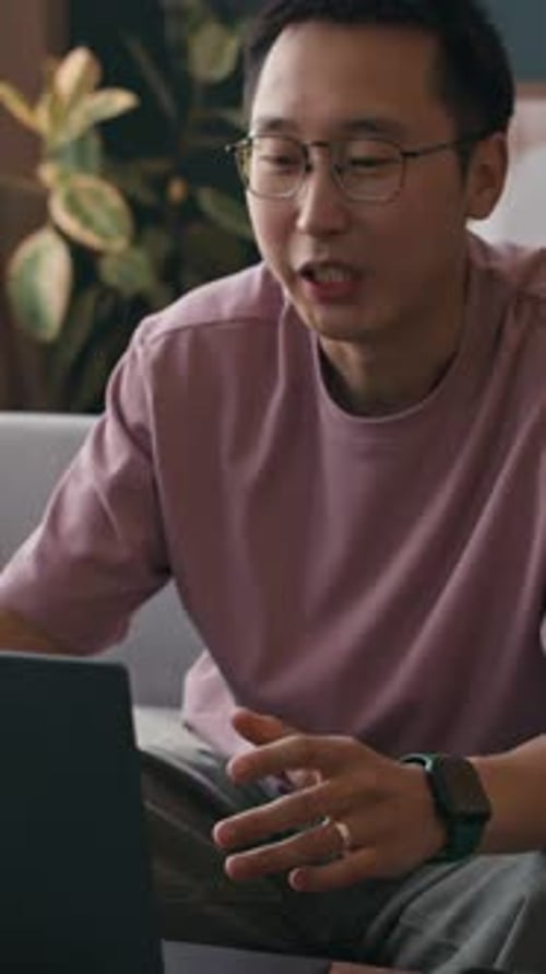 Young Man Drinking Tea Calling on Video via Laptop in Home Office