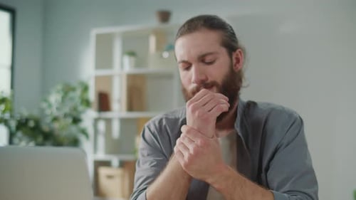 Man Massages Wrist in Home Office Close-Up
