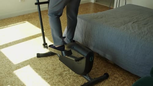Woman Exercising on Elliptical Machine in Bedroom