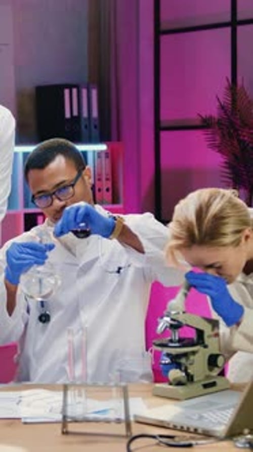 Scientists Working with Flask and Microscope in Lab