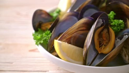 fresh mussels with herbs in a bowl with lemon