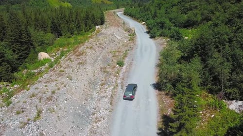 Car moves along dusty road among mountains in gorges.