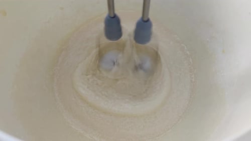Electric Mixer Blending Yellow Ingredients in Bowl