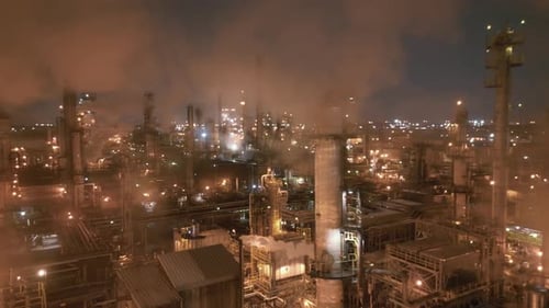 Night aerial shot of a refinery releasing heavy smoke from installations