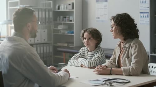 Caring Mother and Her Young Son Consulting with Doctor in Pediatric Clinic