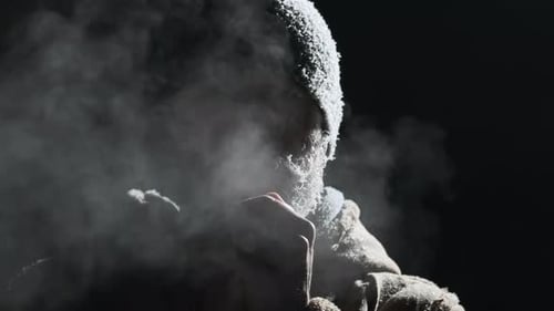 Un homme au visage gelé. Un jeune homme adulte à la barbe glacée et au chapeau respire à l'extérieur à une température inférieure à zéro