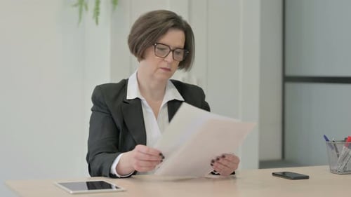 Old Businesswoman Reading Documents in Office, Paperwork