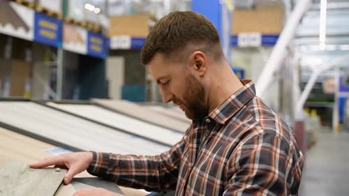 A Man Looks at Different Types and Colors of Floor Coloring in a Store