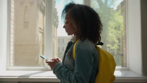 Side View African American Female Student Walk University Corridor Mobile Phone Using Smartphone
