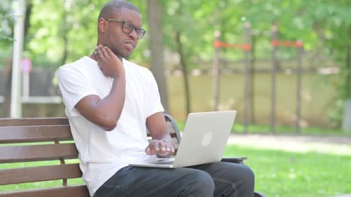 Man Using Laptop Massages Stiff Neck Outdoors