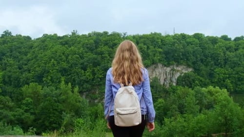 Glückliche junge Frau in blauem Regenmantel in Zeitlupe genießt den Wald im Park True Emotions Open Arms