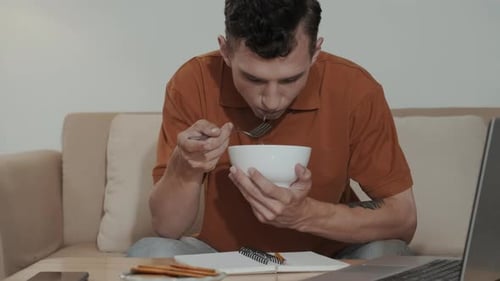 Man Eats Salad While Sitting on Couch