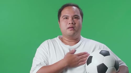 Close Up Of Asian Man With A Ball Singing National Anthem While Cheering Soccer On Green Screen