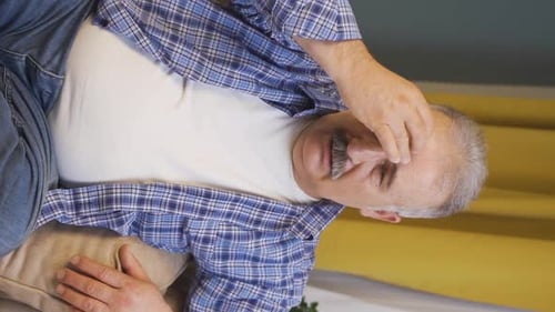 Vertical video of Old man with migraine is experiencing pain.