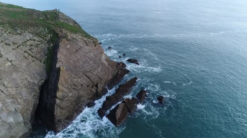 Dramatic coastal cliff meets the ocean waves. Drone view. 4K.