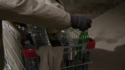 Gloved Hand Placing Bottles Into Shopping Cart