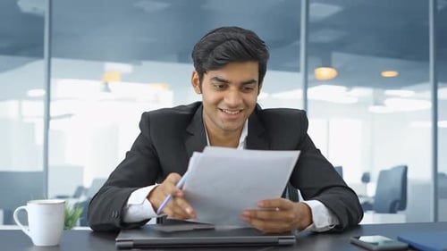 Smiling Man Reviewing Documents in Modern Office