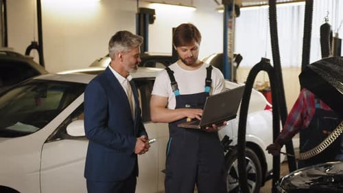 Engineer with Laptop Makes Computer Diagnostics of the Car Engine in Autoservice