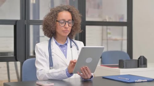 Hispanic Female Doctor Working on Digital Tablet in Hospital