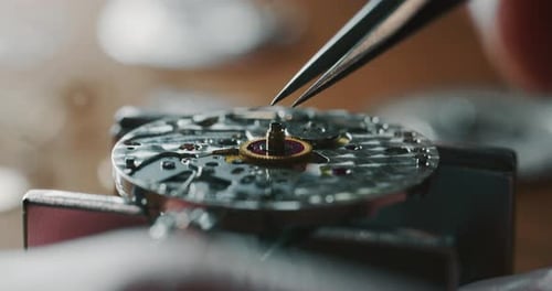 Slow motion close up of a professional watchmaker repairer working on a luxury mechanism watch gea