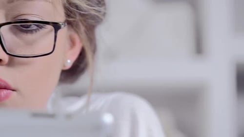 Woman Wearing Glasses Looking at Tablet in Home
