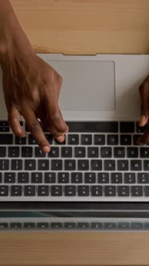 Vertikale Ansicht der Hände einer schwarzen Frau, die am Laptop arbeitet