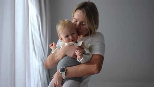 Mother Holds Smiling Infant near Window