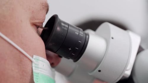 Medical Professional Using Microscope in Bright Lab