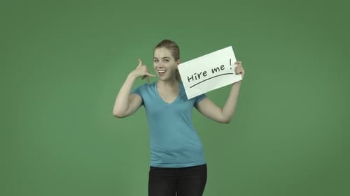 caucasian casual blond girl isolated on green with hire me sign