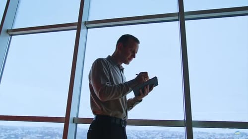 Man Writing in Notebook in Modern Office