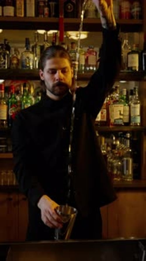 Bartender Pouring Cocktail in Warmly Lit Bar