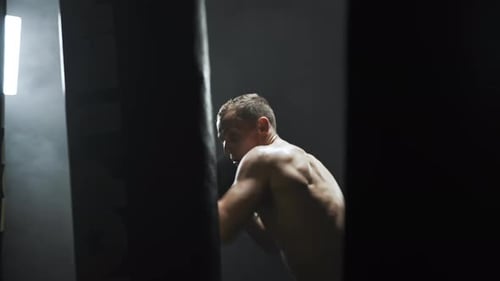 Kickboxer punching and kicking a boxing bag during his training,gym.