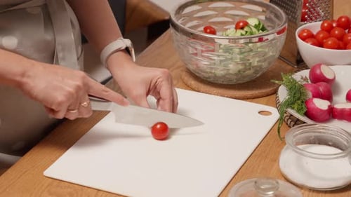 Person Cutting Cherry Tomatoes in Kitchen for Salad