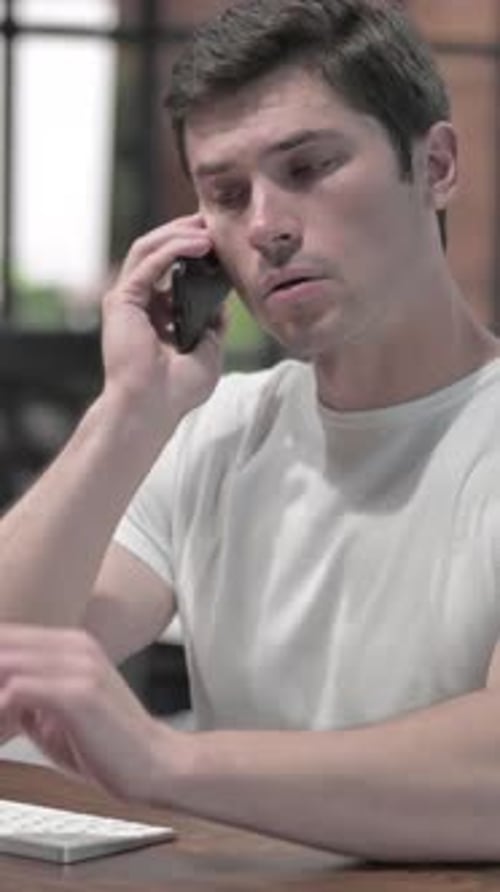 Man in White Shirt Talking on Smartphone Indoors