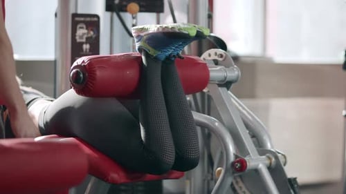 Fitness Woman Training Leg Flexion In Sport Simulator In Gym. Sport Woman Doing Leg Exercises On ...