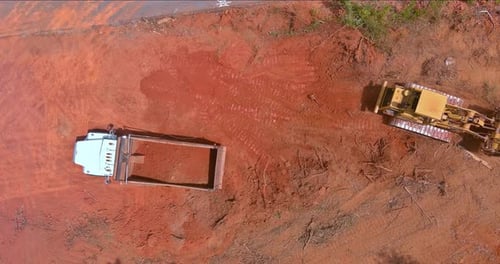 Bulldozer Clearing Dirt Next to Dump Truck Aerial