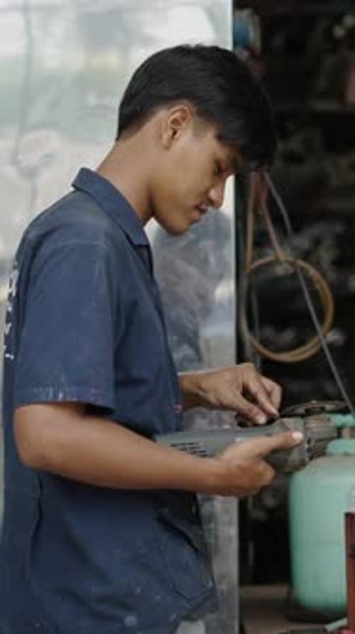 Young Handsome Real Worker Using an Angle Grinder and Smiling to the Camera FHD Vertical Video