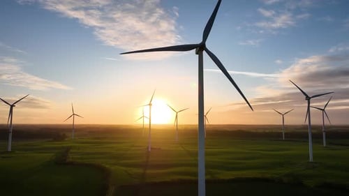 Aerial footage of large spinning wind turbine in agriculture fields.