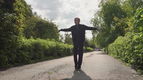 Young Man Dances down Path Lined with Greenery