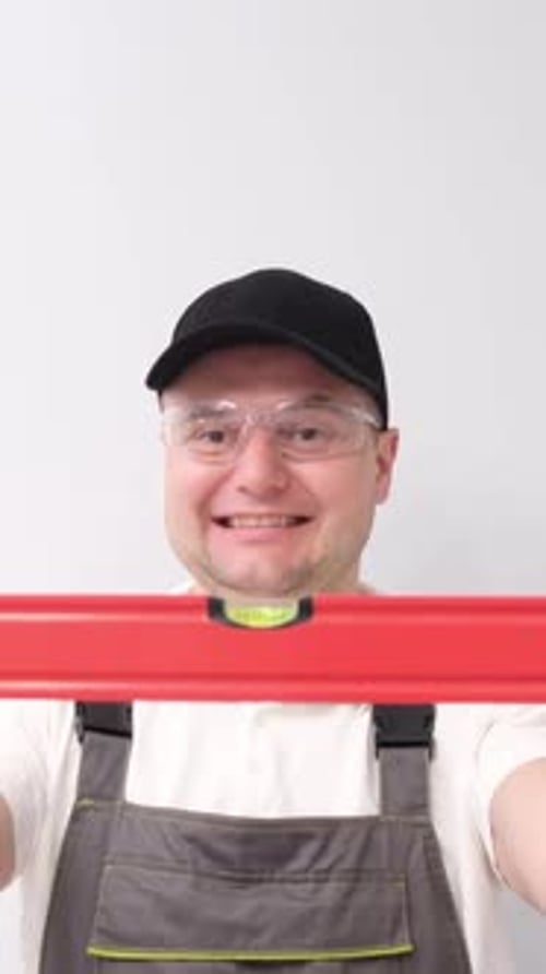 Smiling Construction Worker with Water Level in Hands in Studio on White Background